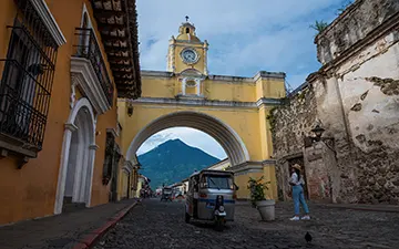 Hunahpú Volcano framed by Arch with tuk tuk and girl posing, Guatemala